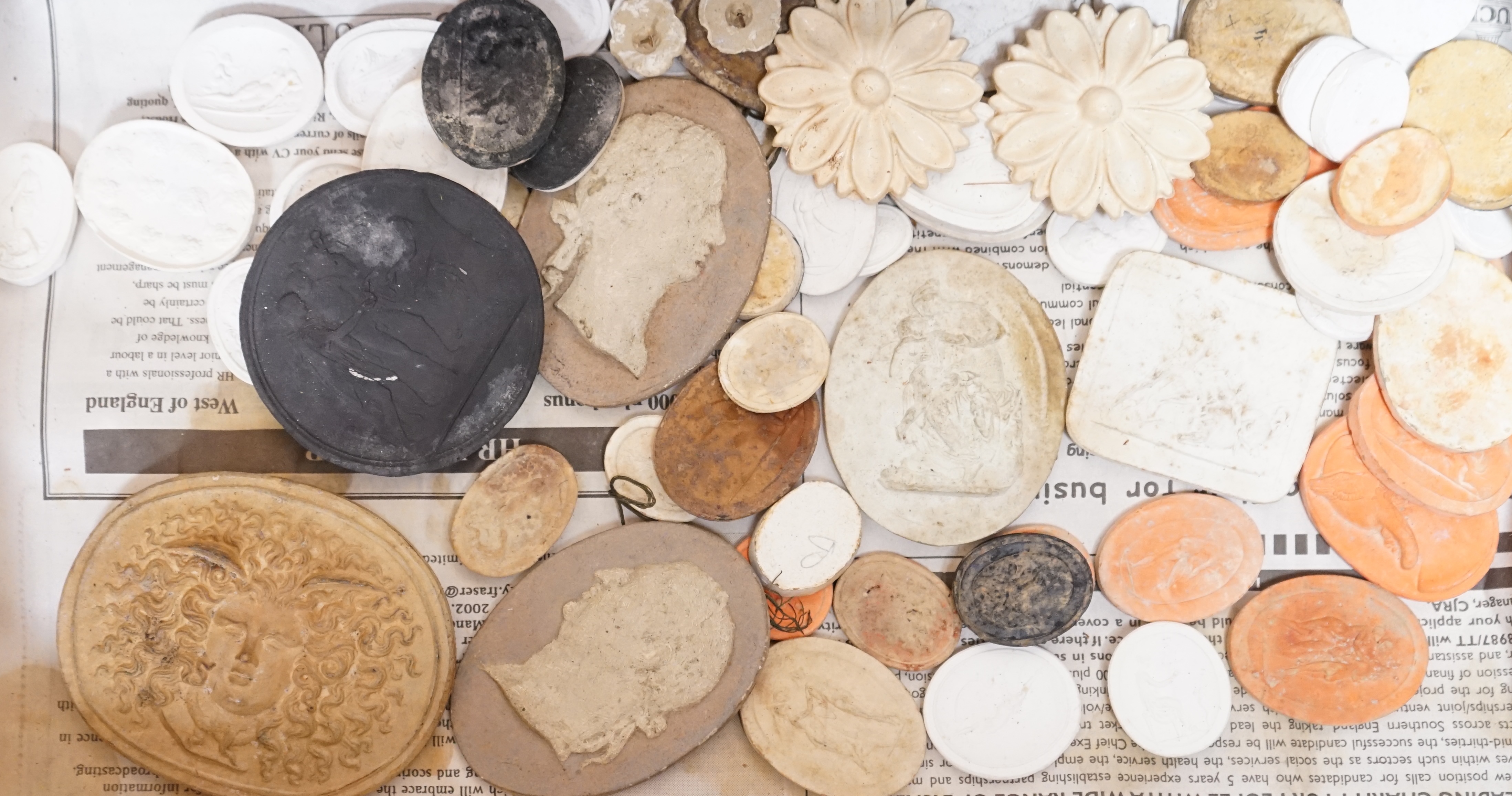 A case containing a collection of various plaster cameos and moulds. Condition - varies